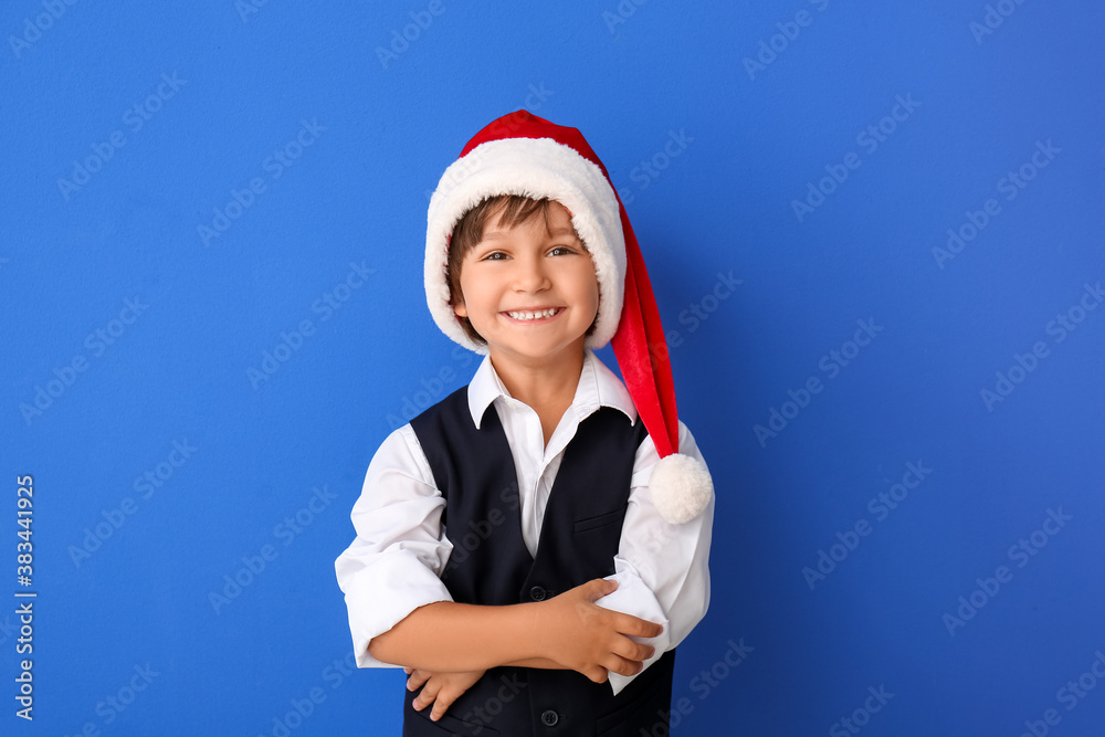 Cute little boy in Santa hat on color background