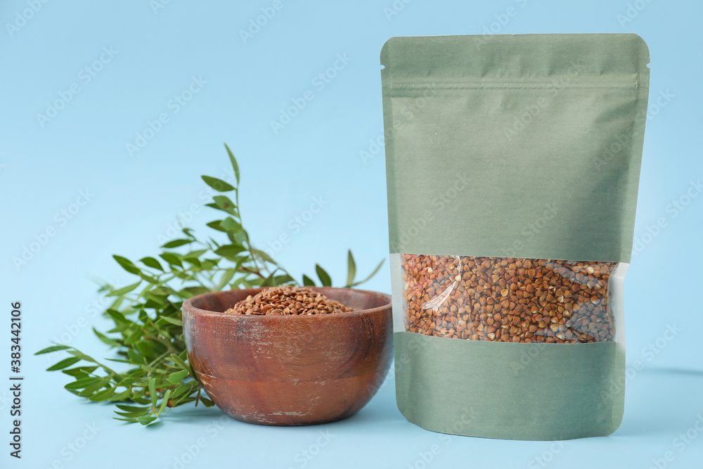 Bag and bowl with buckwheat groat on color background