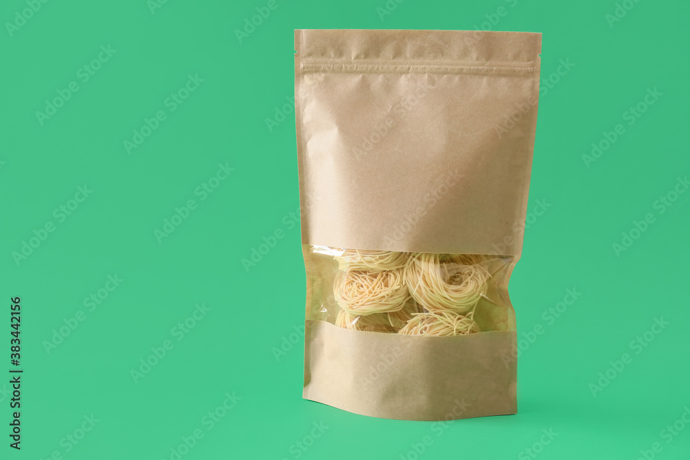 Paper bag with pasta on color background