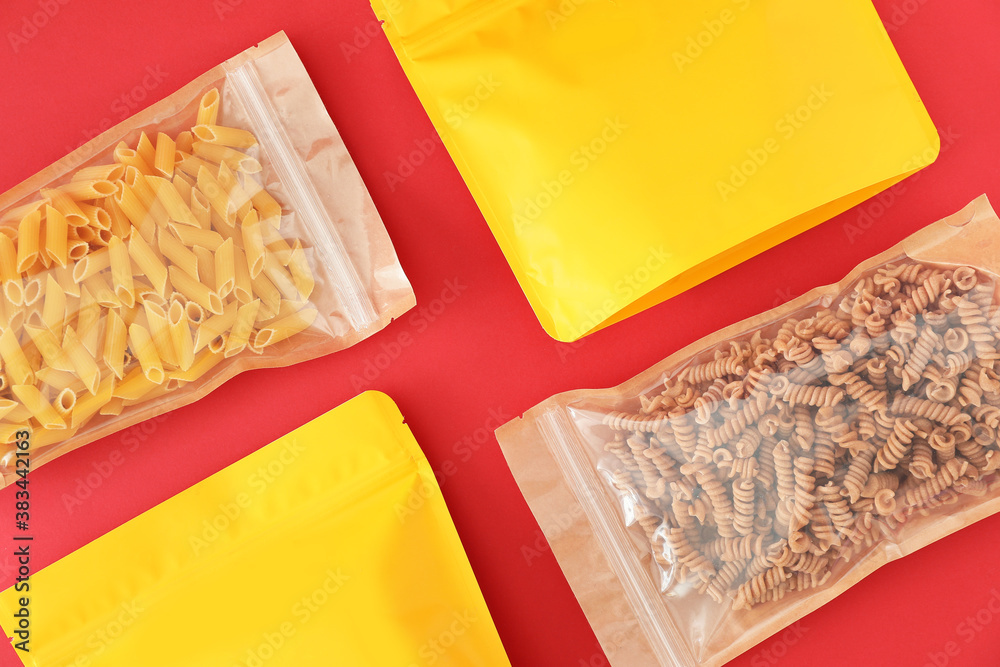 Bags with different pasta on color background