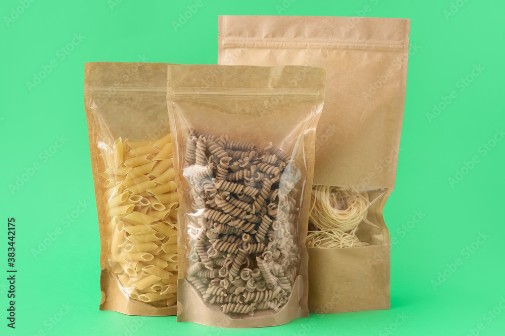 Bags with different pasta on color background