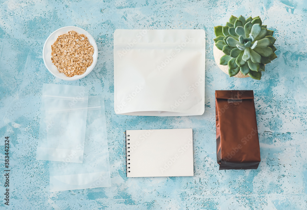 Bags with oat groat and notebook on color background