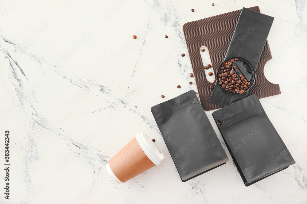 Blank bags with coffee beans and cup on white background