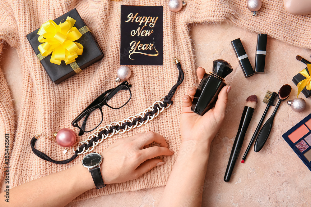 Hands with Christmas decor and cosmetics on color background