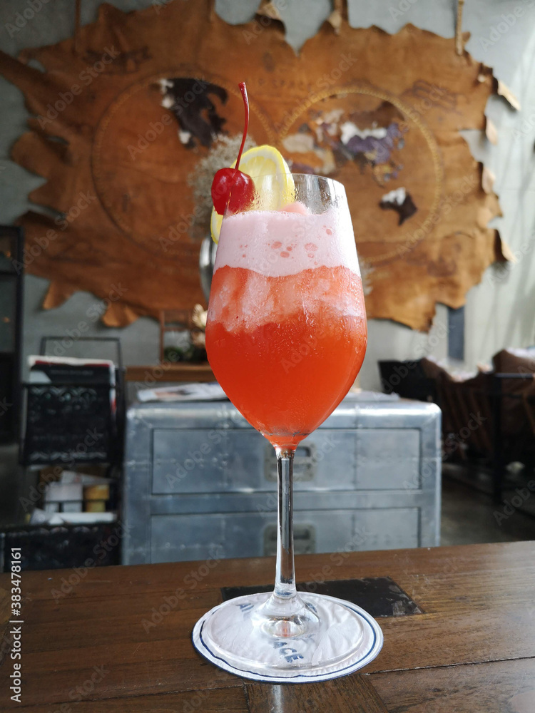 fruit punch iced cocktail on the wooden table with blurred background