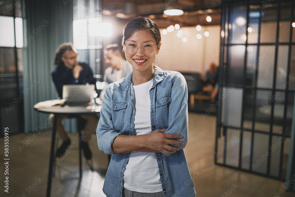 Asian businesswoman smiling with colleagues sitting in the backg