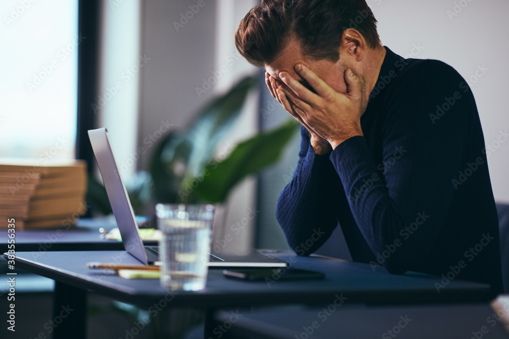 Businessman with his head in his hands at a desk