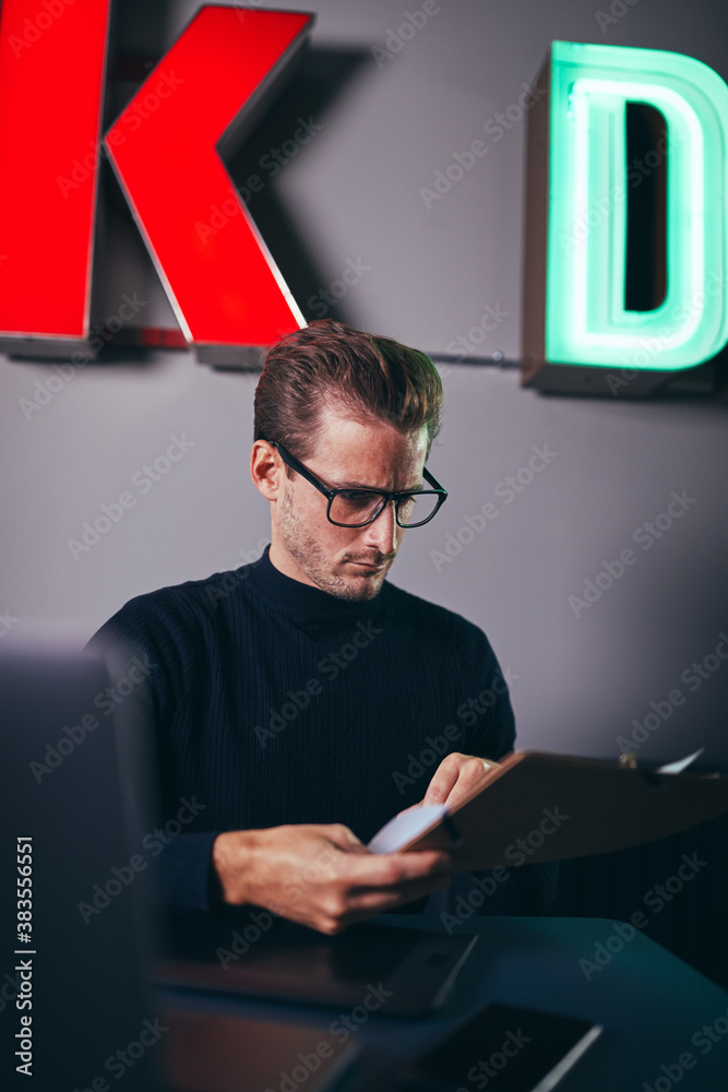 Young businessman reading documents at his desk in an office