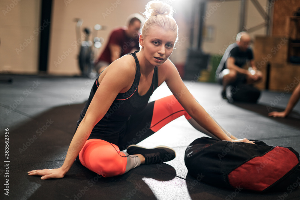 Woman sitting in a gym after a weight bag workout