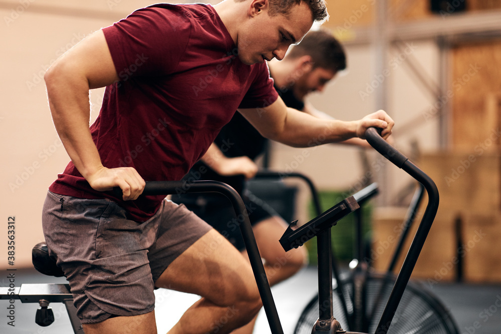 Fit young man riding a stationary bike at the gym