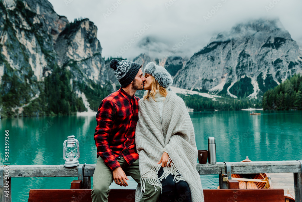 Romantic kiss of a couple of adults visiting an alpine lake at Braies Italy. Tourist in love spendin