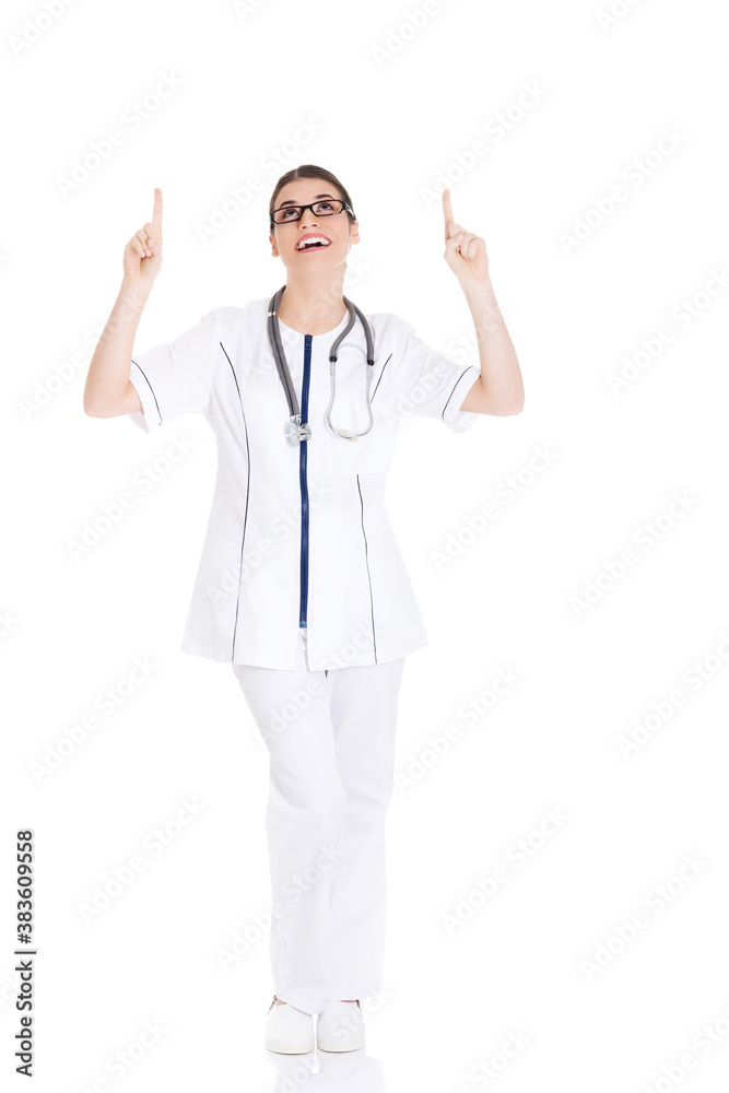 Beautiful young woman doctor pointing up.