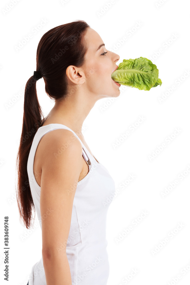 Beautiful woman with leaf of lettuce in mouth.