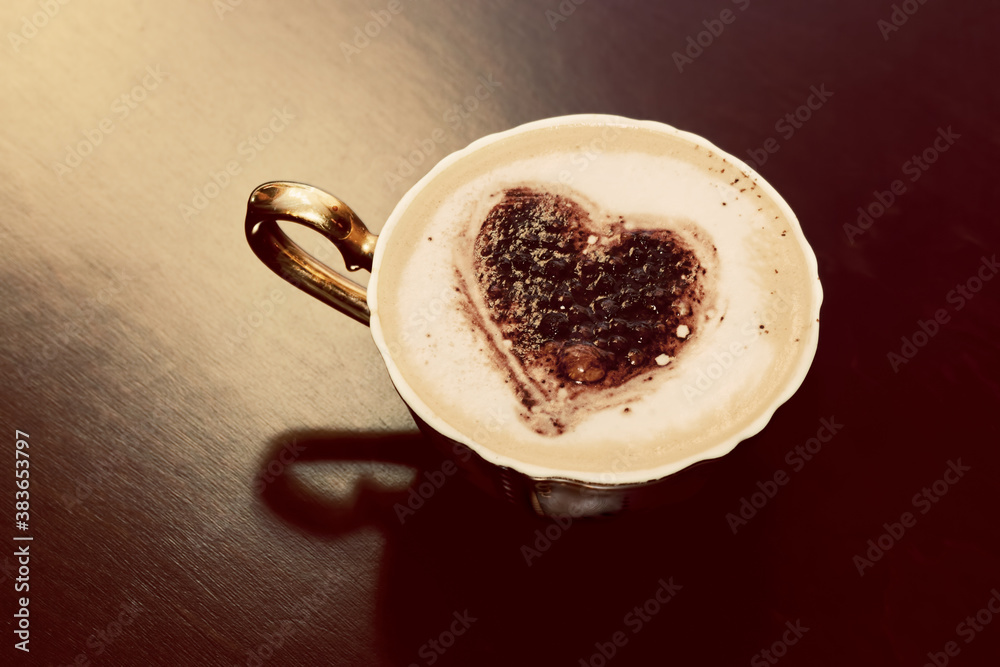 Cup of coffee with chocolate heart shape on milk foam.