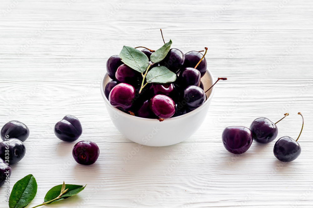 Plate of ripe red cherries with leaves, close up