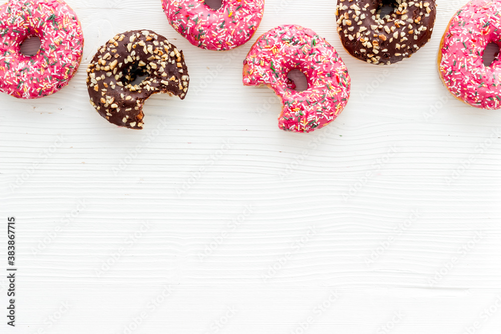 Donuts flat lay pattern on white wooden background, top view