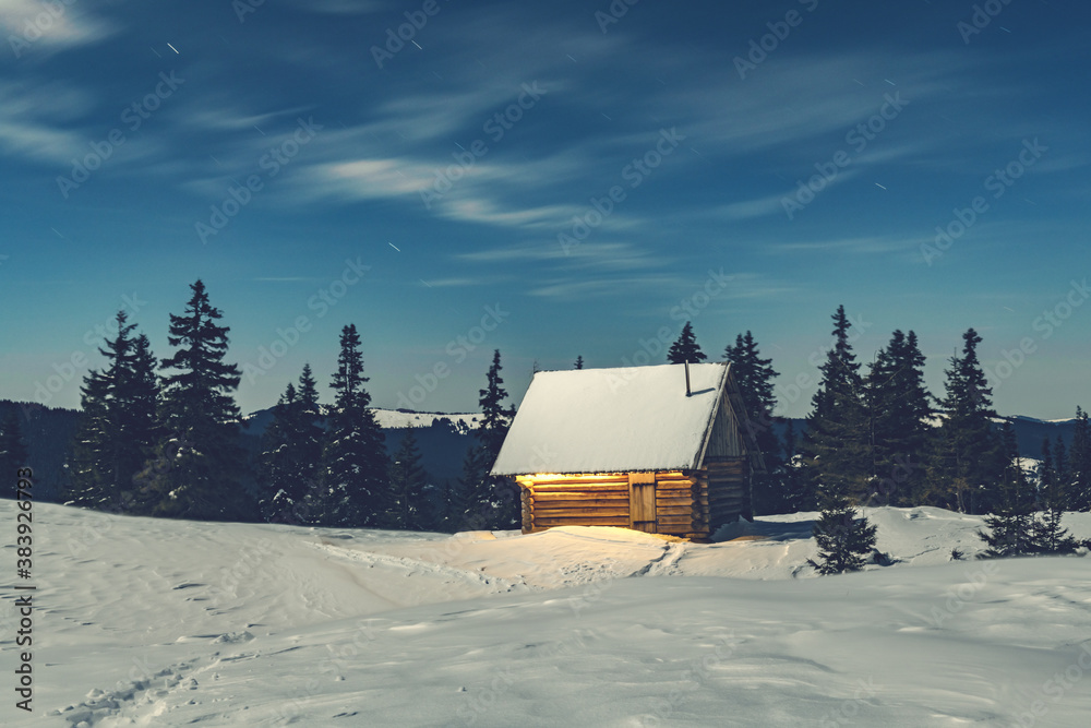 Fantastic winter landscape with wooden house in snowy mountains. Christmas holiday concept