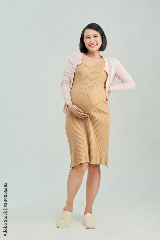 cheerful pregnant asian girl touching belly on white