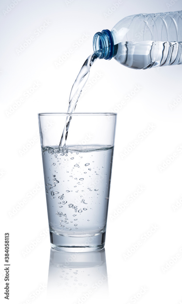 Pour water into a clear glass placed on a white background.