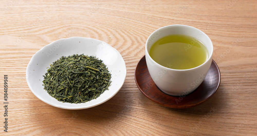 Green tea and tea leaves on a wooden tray