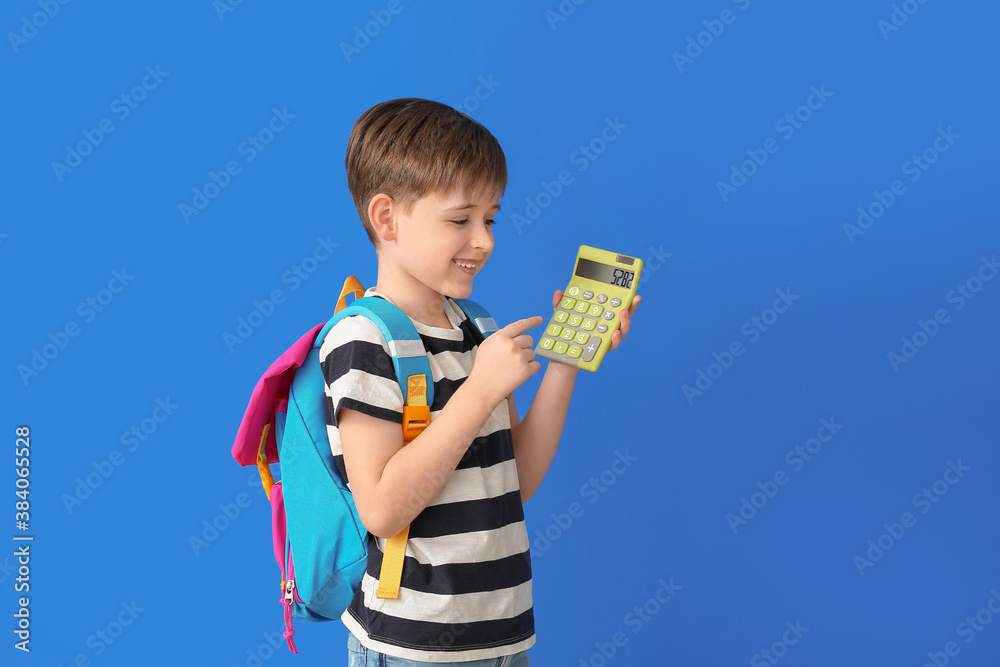 Little schoolboy with calculator on color background