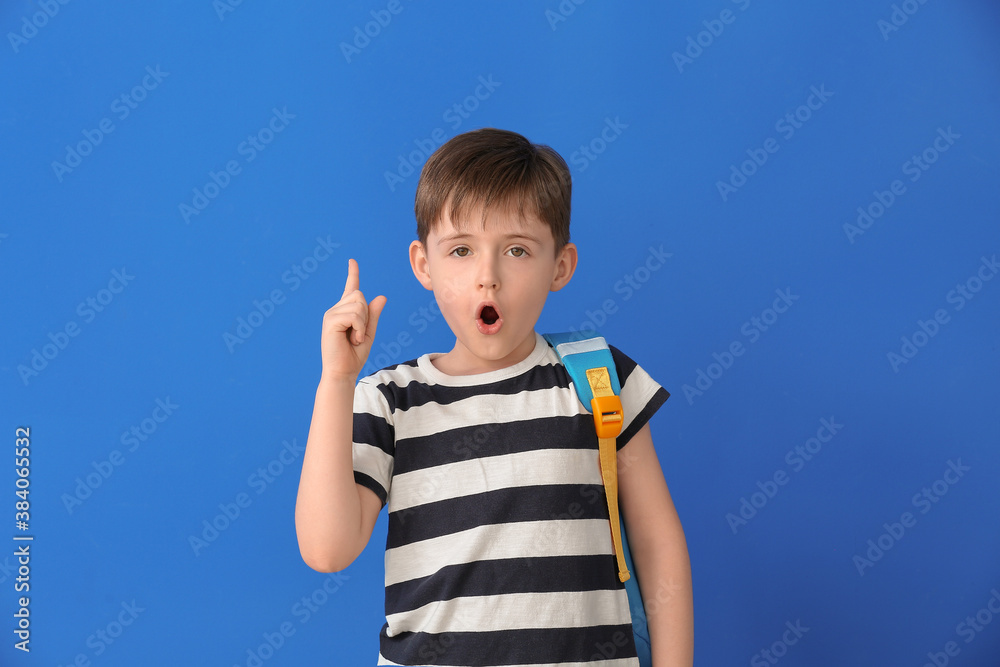 Little schoolboy with raised index finger on color background