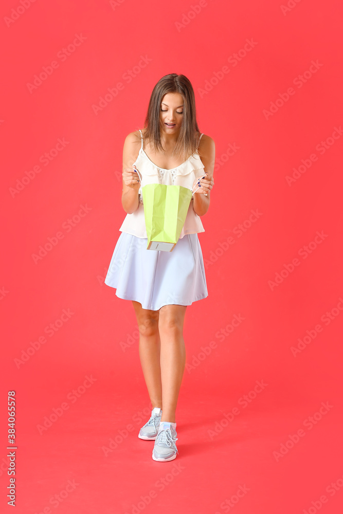 Beautiful young woman with shopping bags on color background