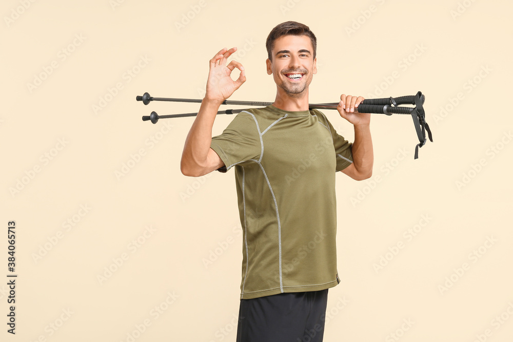 Young man with walking poles showing OK on color background