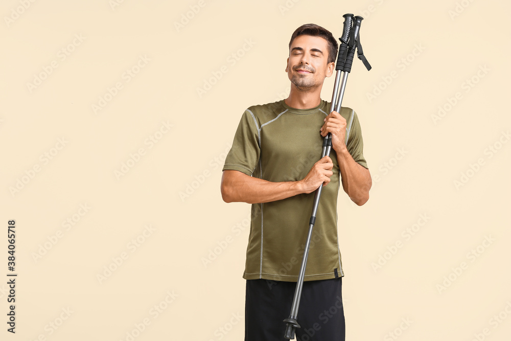 Young man with walking poles on color background