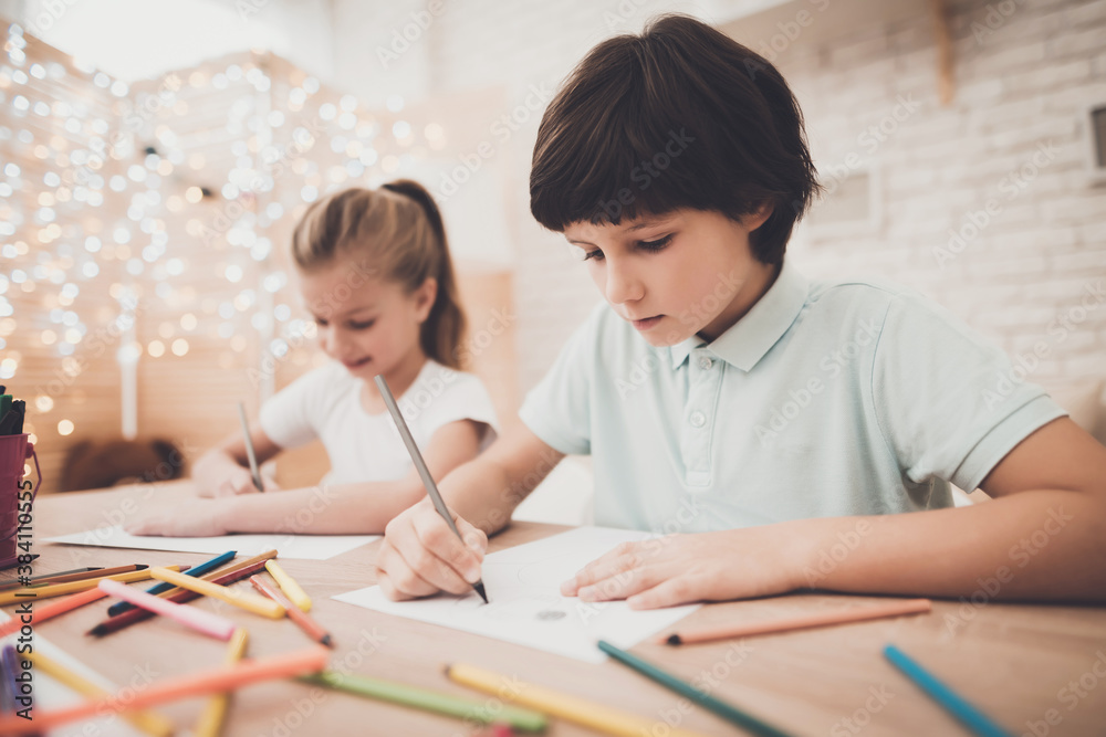 Boy with a girl sits at table and draw. 