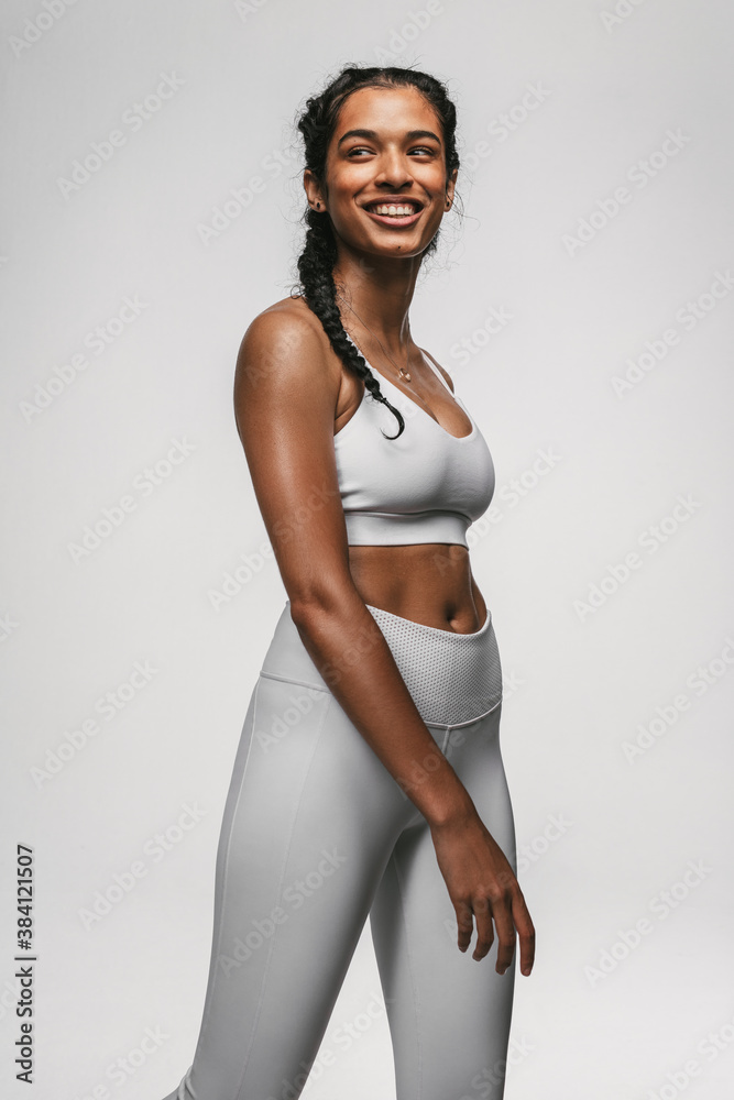 Smiling female athlete walking against white background