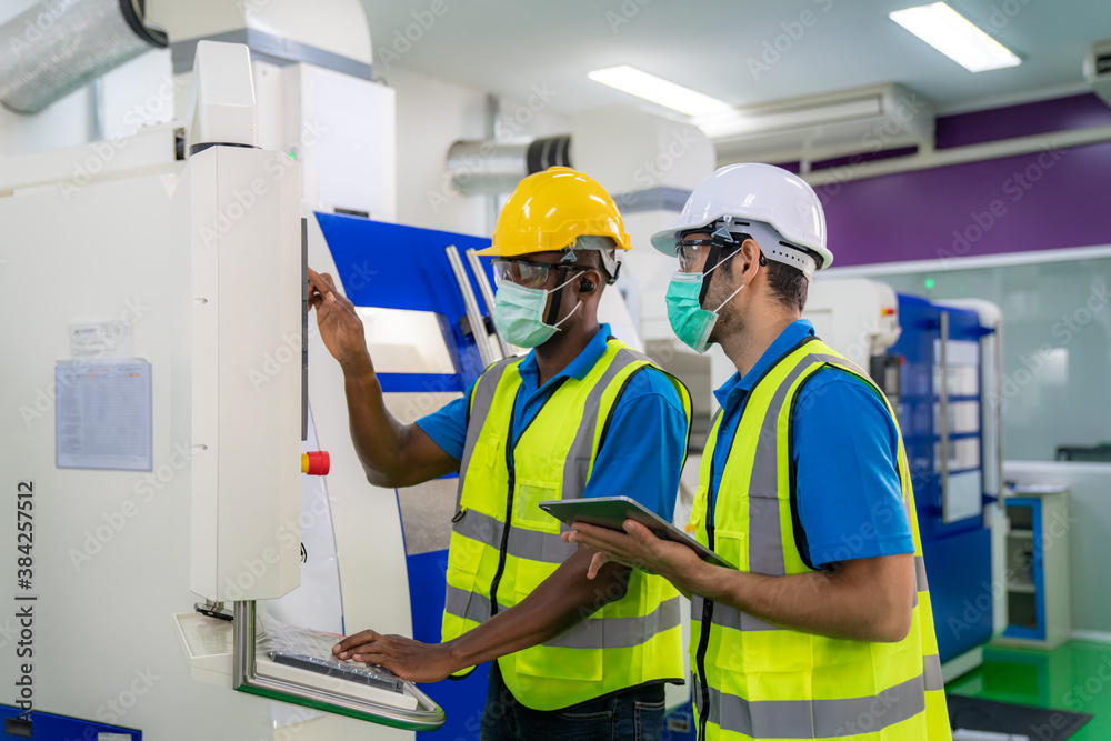 Asian industrial engineers and worker in hard hats discuss product line while using digital tablet i