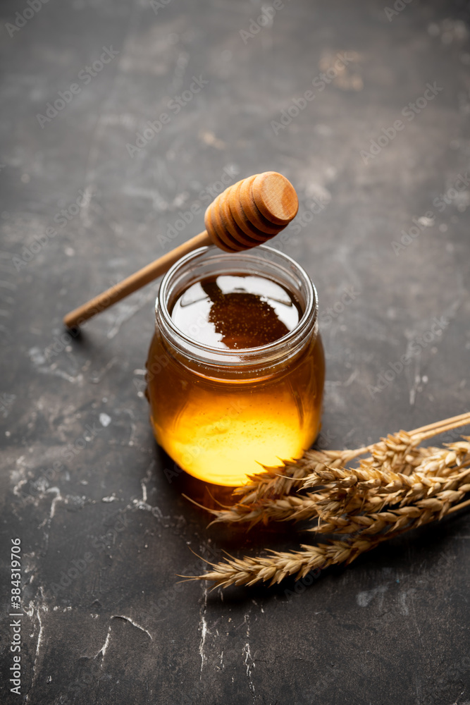 Jar with freshly harvested liquid honey on the old wooden table. Selective focus.