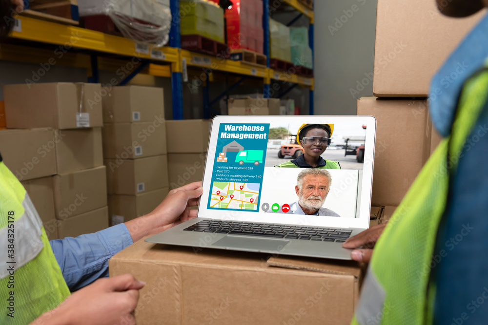 Warehouse staff talking on video call at computer screen in storage warehouse . Online software tech