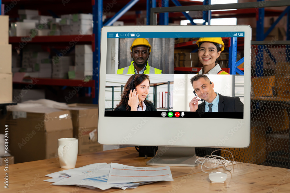 Warehouse staff talking on video call at computer screen in storage warehouse . Online software tech