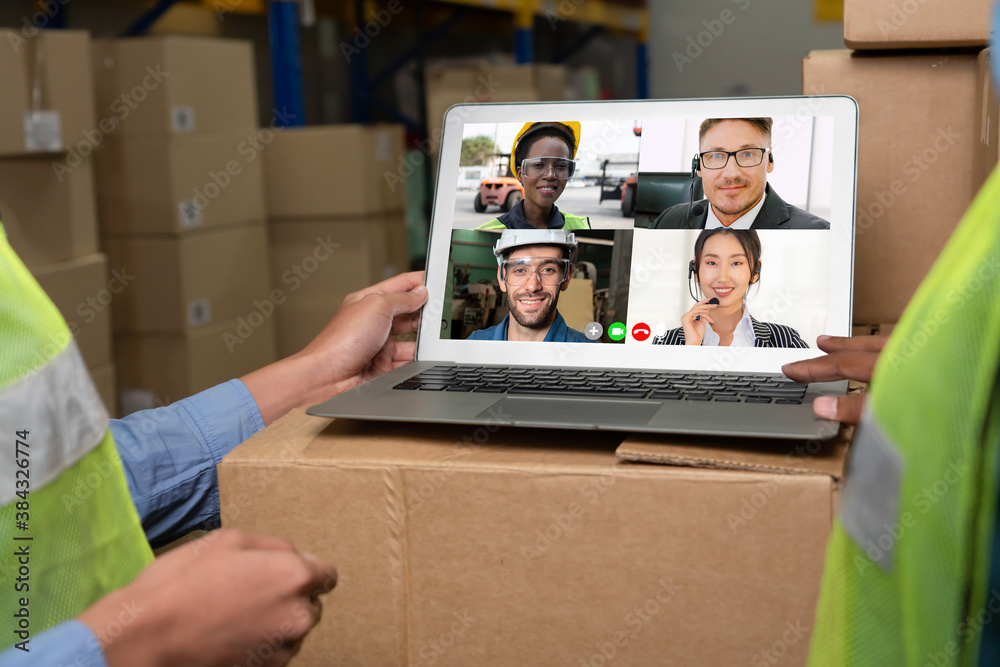 Warehouse staff talking on video call at computer screen in storage warehouse . Online software tech