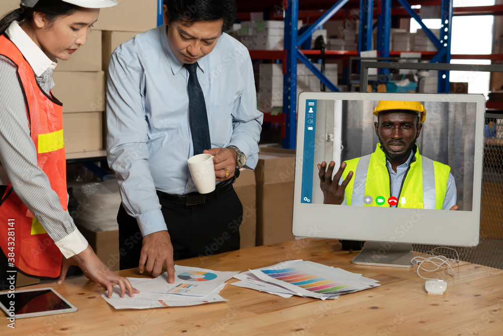 Warehouse staff talking on video call at computer screen in storage warehouse . Online software tech