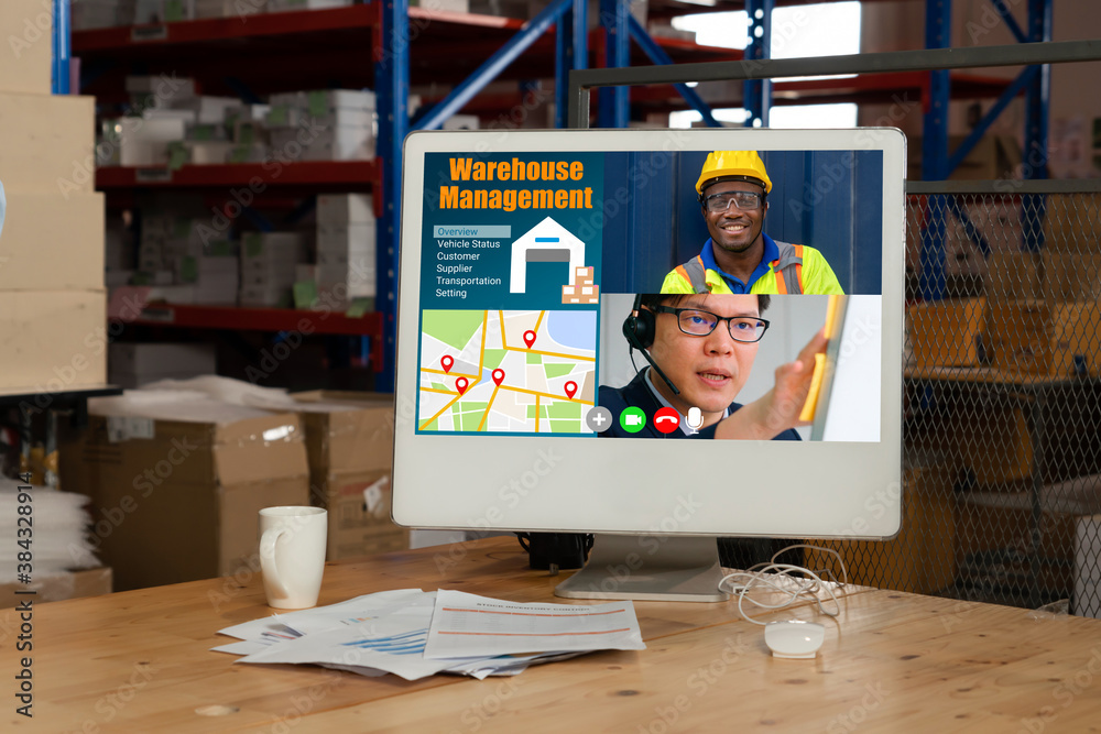 Warehouse staff talking on video call at computer screen in storage warehouse . Online software tech