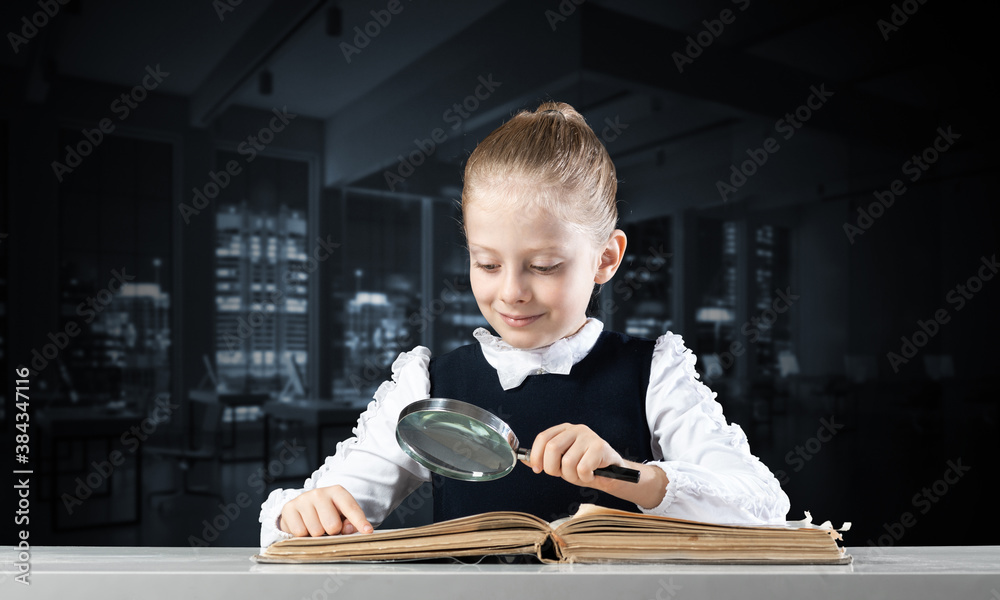 Little girl sitting at desk with magnifier