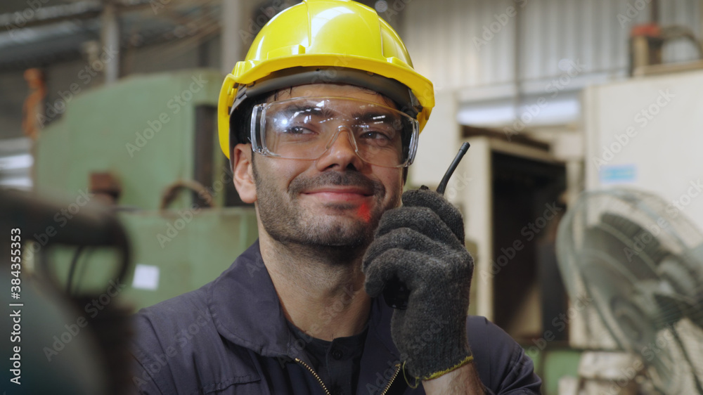 Factory worker talking on portable radio while inspecting machinery parts . Industrial and engineeri