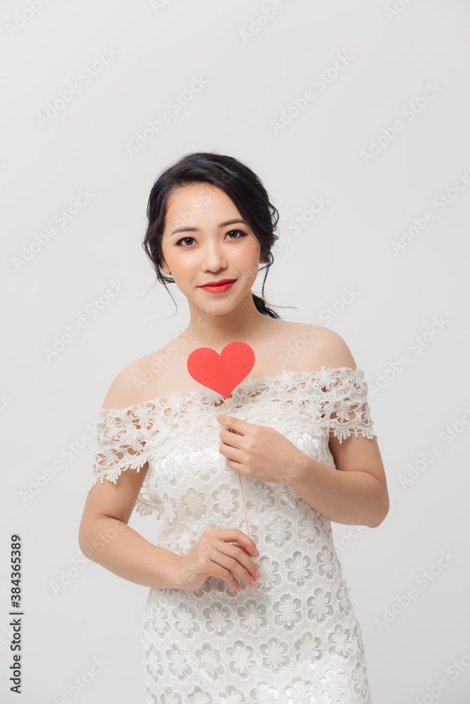 Elegant Asian woman holding a parper heart and standing isolated over white background.