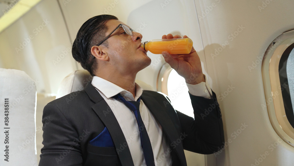 Businessman have orange juice served by an air hostess in airplane . Business trip travel concept .