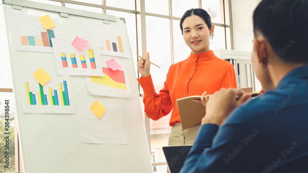 Young woman explains business data on white board in casual office room . The confident Asian busine