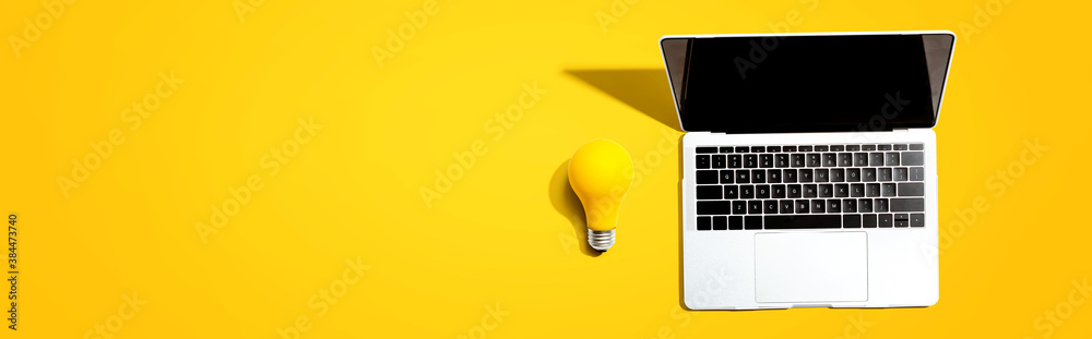 Laptop computer with a yellow light bulb from above