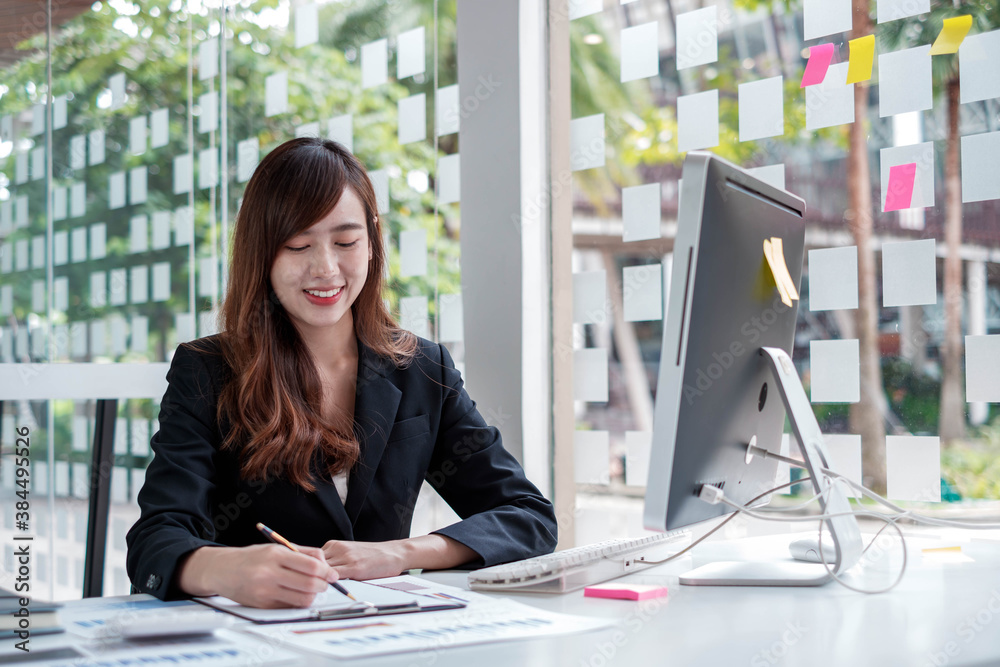 A serious business woman in a suit is reviewing and taking notes of the companys performance chart