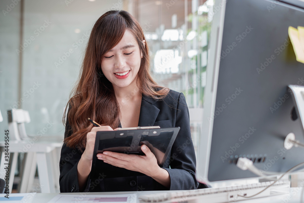 A serious business woman in a suit is reviewing and taking notes of the companys performance chart