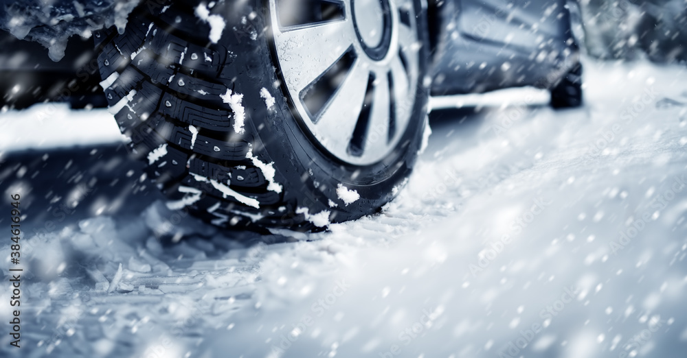 Closeup of the car tire on winter road covered with snow in snowfall