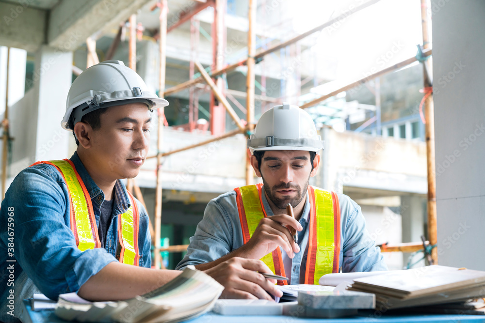 Young Asian engineers and caucasian engineer colleagues at site inspector and discuss together using