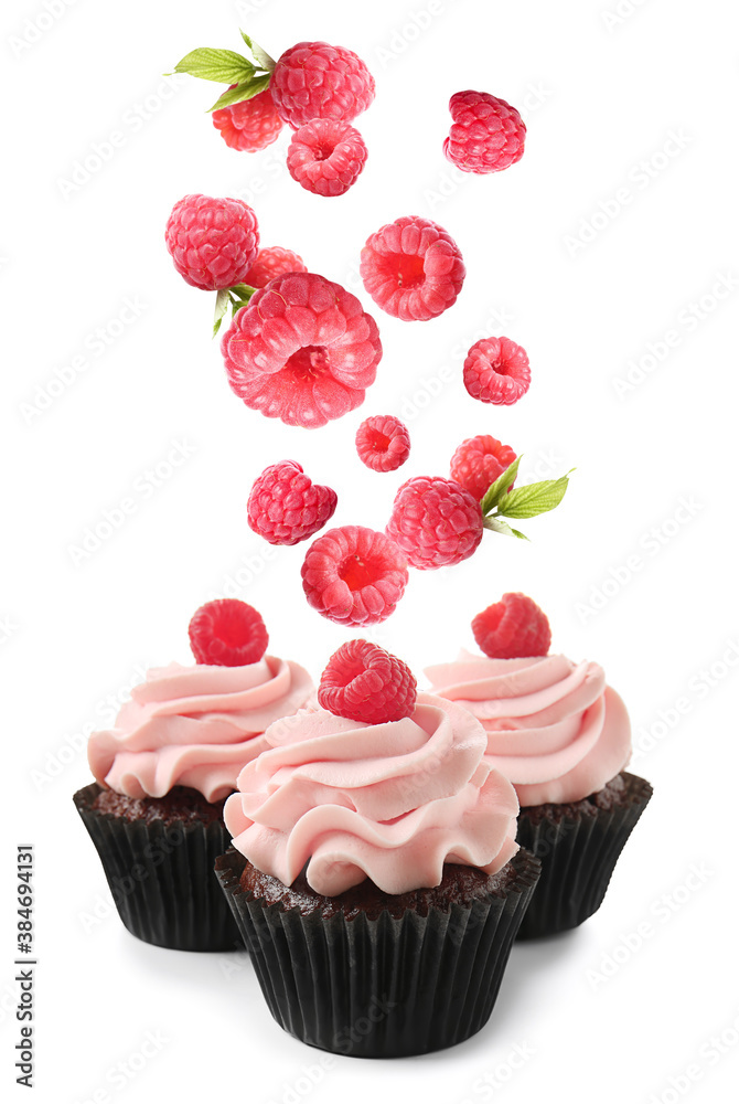 Delicious cupcakes and falling raspberry on white background