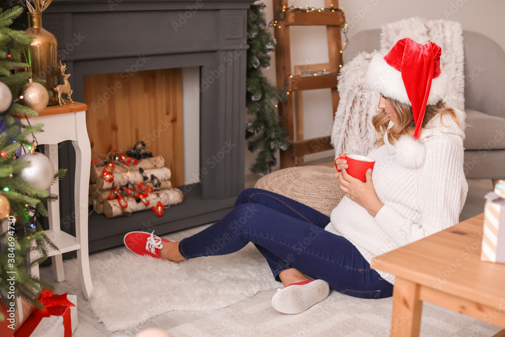 Beautiful pregnant woman drinking cacao at home on Christmas eve